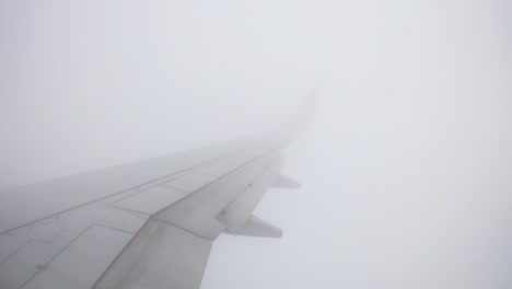 Fensterplatz-Weitwinkel-Flügelansicht-Aufnahmen-Des-Fluges,-Während-Er-Durch-Turbulenzen-Zwischen-Wolken-Zu-Einem-Klaren-Himmel-Mit-Blick-Auf-Die-Stadt-Unten-Fliegt