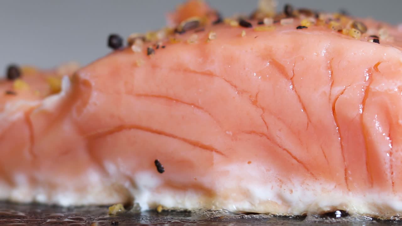 hermoso filete de salmón fresco cocinado y sazonado en una sartén caliente, primer plano macro