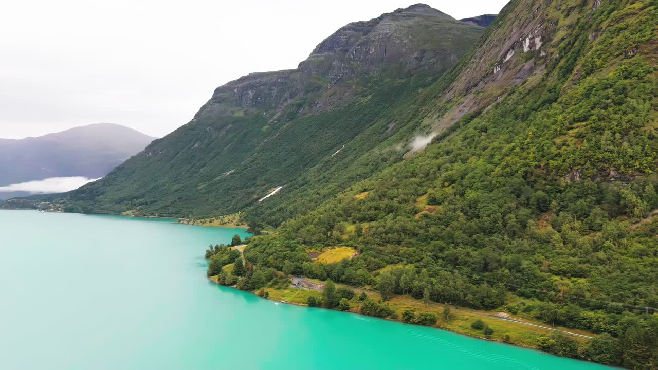 Aerial view of Lake shoreline of Lovatnet in Norway, showcasing turquoise waters surrounded by mountains and forests