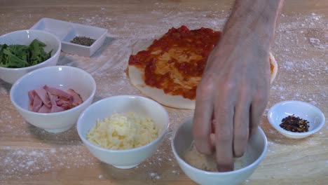 topping a fresh homemade pizza with grated parmesan