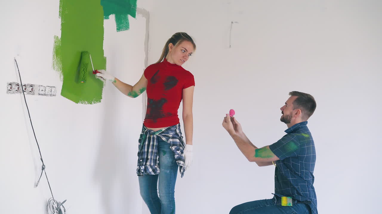 el hombre se propone con un anillo a una chica emocional en una habitación luminosa.