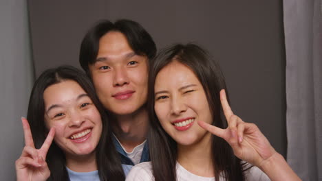 group of friends in photo booth having fun posing for portrait and pulling faces shot in real time