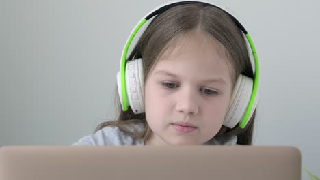 caucasian school girl pupil video call online via internet tutor on computer laptop with headphones