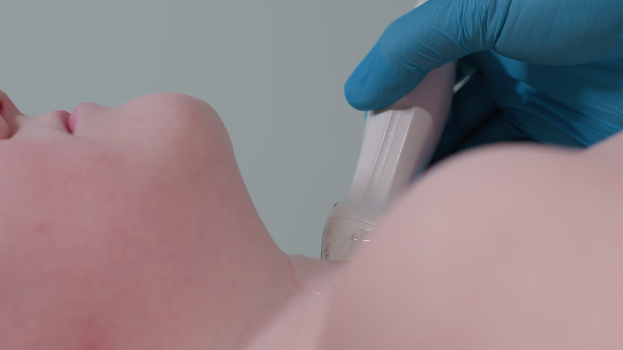 Aerial view of teenager lying barechested while laboratory scientist in blue gloves conducts diagnostic examination using ultrasound transducer on neck region with precision in clinical setting
