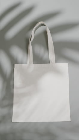 vertical video of leaf shadow over white bag on white background