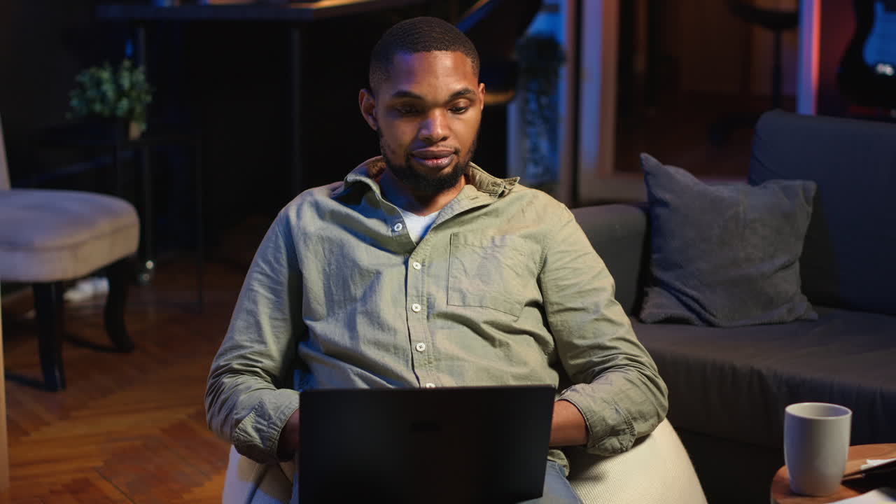 Vertical Video Focused black person multitasking on laptop in stylish loft space