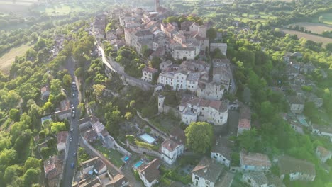 drone aerial view in france countryside small old medieval brick town on a mountain top surrounded by green fields vertical panning on a sunny day in cordes sur ciel