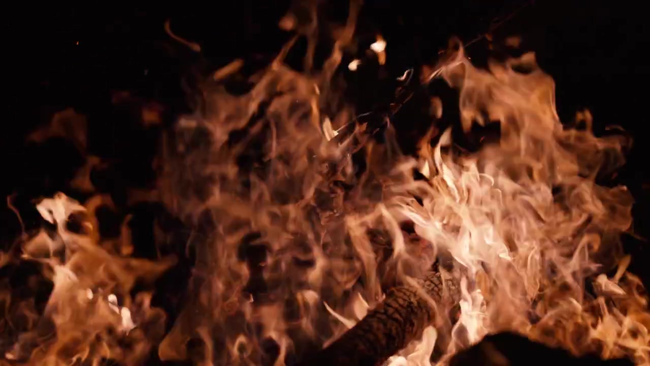 Flickering Bonfire Flames and Sparks Against a Dark Background