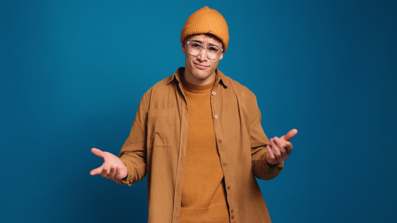 Man in beanie and glasses shrugging