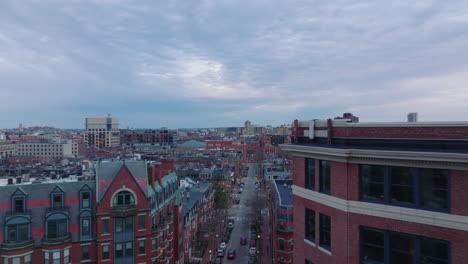 Forwards-fly-above-apartment-buildings-with-red-brick-facades-in-residential-urban-borough.-Aerial-footage-at-dusk.-Boston,-USA