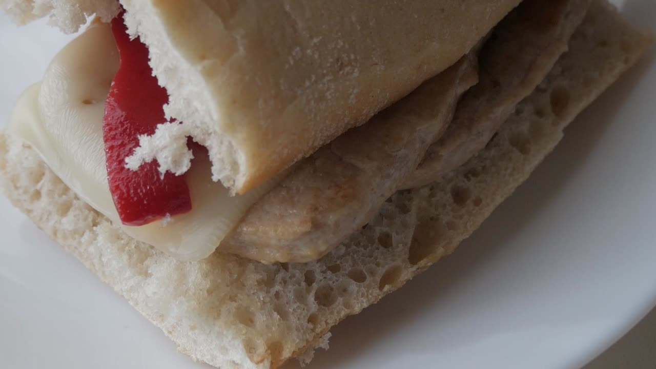 Freshly prepared pork tenderloin sandwich with cheese and red peppers, close-up
