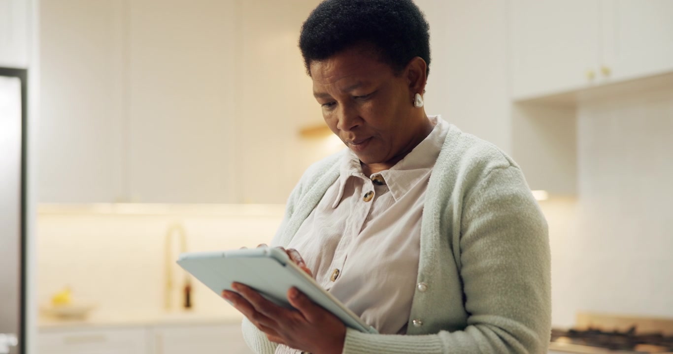 Mature Woman Using a Digital Tablet in a Modern Kitchen