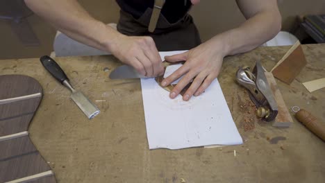 artesano aplanando una pieza de madera con un raspador en el taller