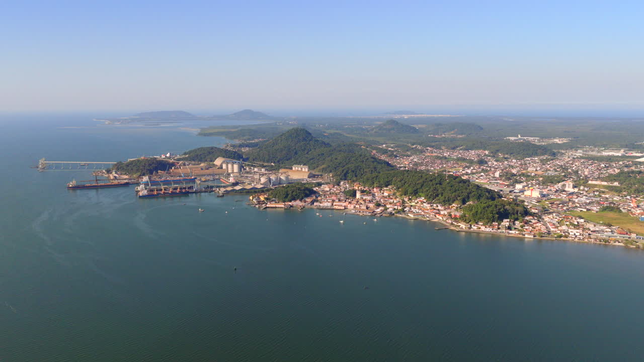 Slow, cinematic right pan reveals coastal cityscape, ocean vista, and distant horizon during sunny afternoon in São Francisco do Sul, Santa Catarina