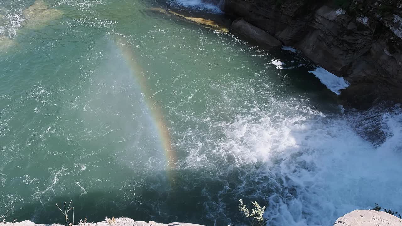 el arco iris de colores etéreos aparece en la niebla que sopla de una gran cascada