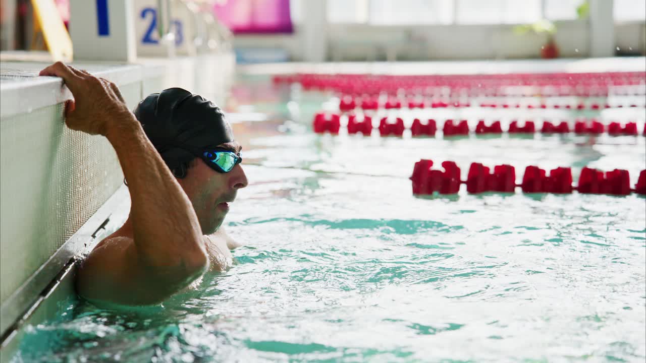A Dedicated Swimmer Takes a Break in the Pool, Reflecting on Performance and Strategy During a Training Session in a Modern Swimming Facility