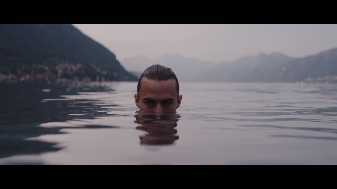 Man swimming in a lake with mountains in the background