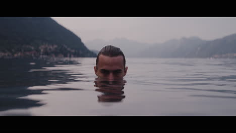 man swimming in a lake with mountains in the background