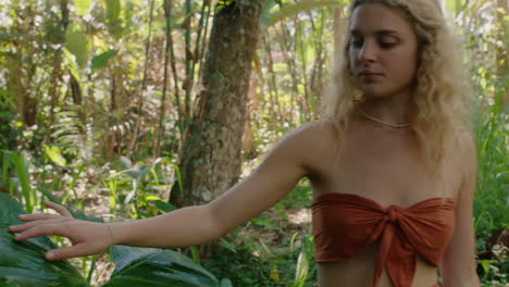 mujer de la naturaleza caminando en el bosque tocando plantas con la mano disfrutando de la belleza natural explorando la exuberante selva tropical sola 4k