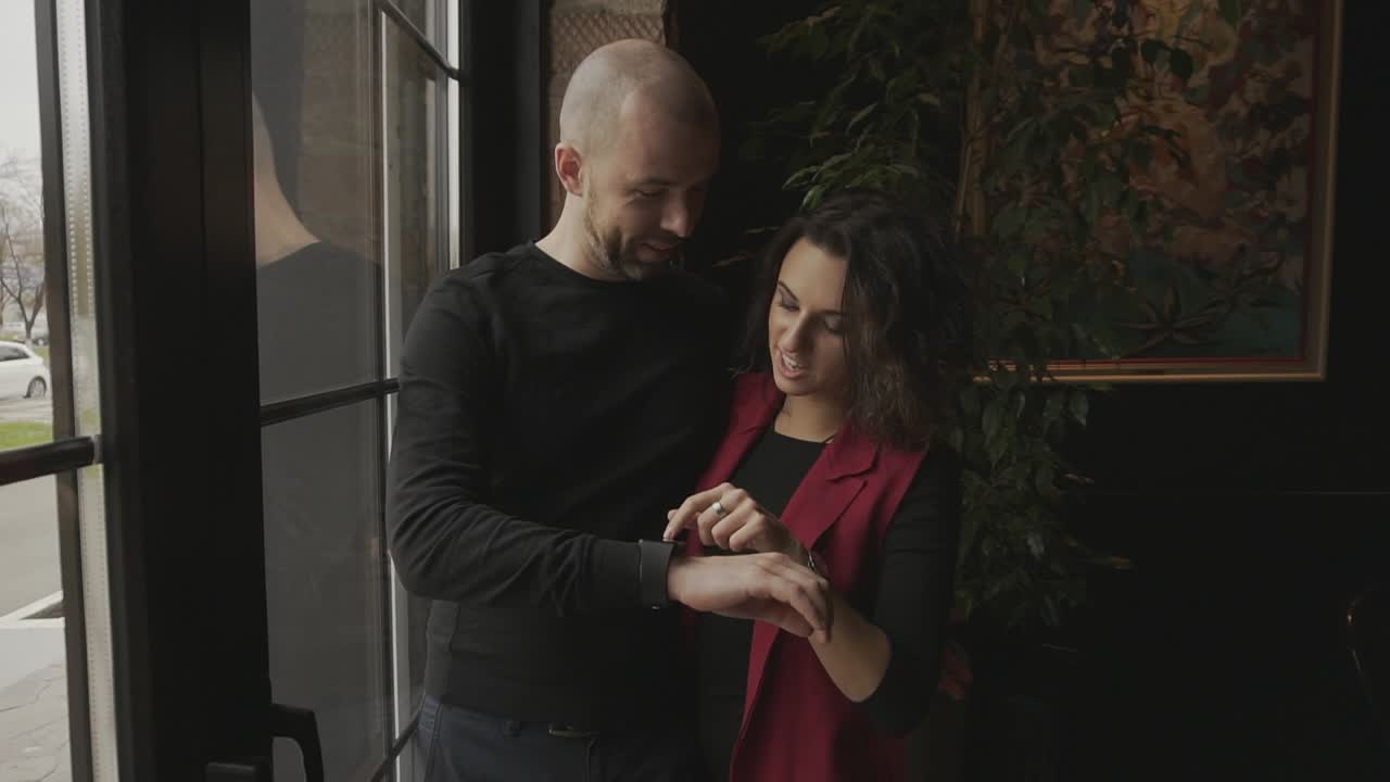 Couple looking at a smartwatch in a cafe