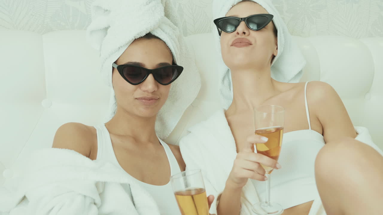 두 명의 여성이 침대에 페인을 마시며 휴식을 취하고 있습니다.
