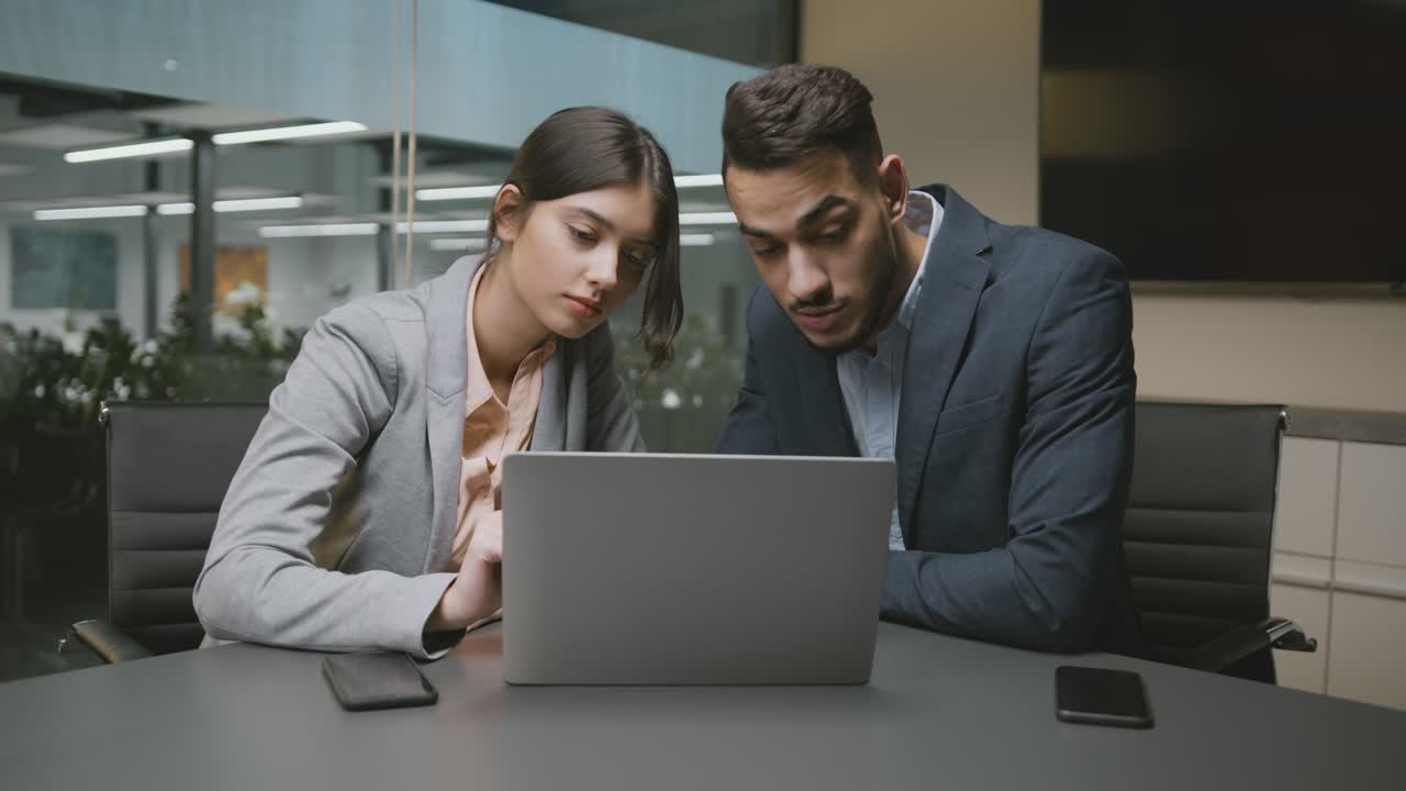 joven mujer de negocios caucásica y hombre de negocios árabe discutiendo estrategia de negocios, haciendo investigación en línea en la computadora portátil