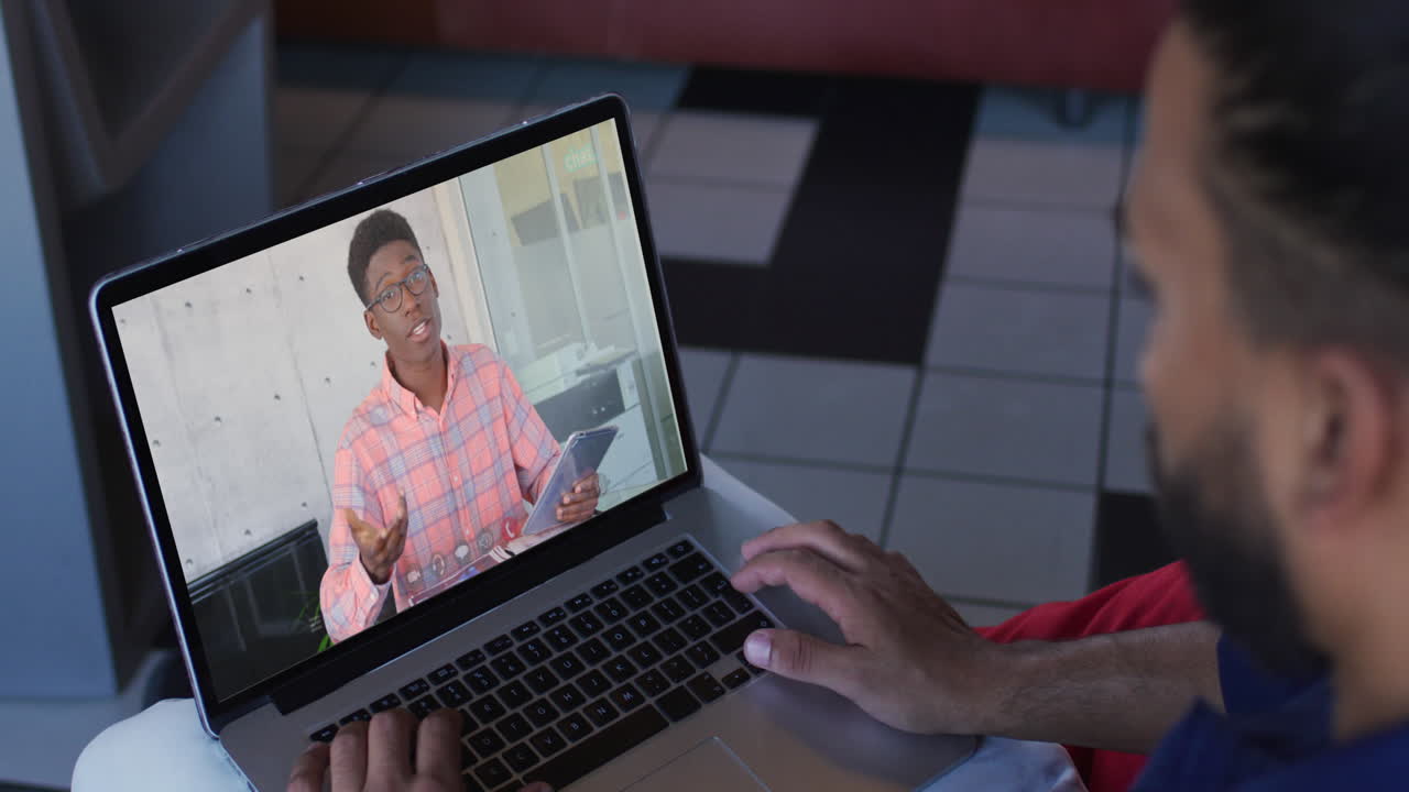 Middle eastern man having a video call with male office colleague on laptop