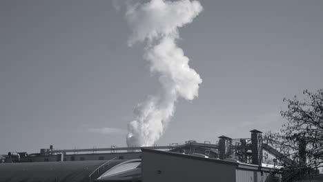 black and white footage of industrial factory with steam going up in the atmosphere