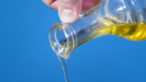 male hand pouring olive oil from glass jug.