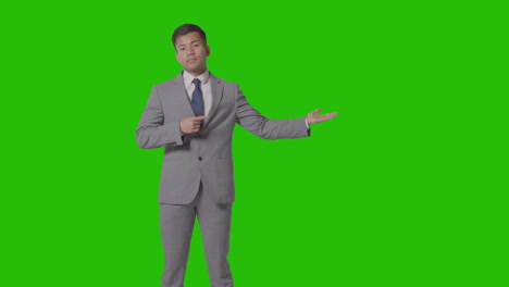 Three-Quarter-Length-Shot-Of-Businessman-In-Suit-Presenting-Or-Showing-Against-Green-Screen-