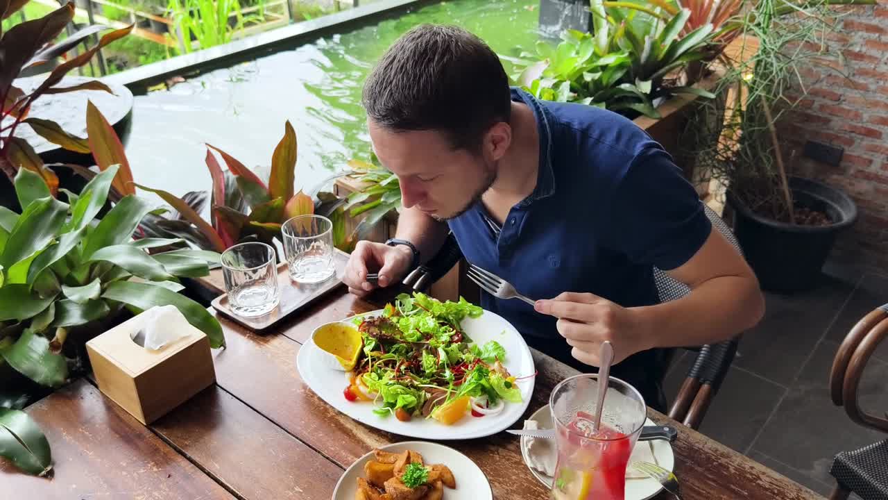 hombre comiendo ensalada en un restaurante