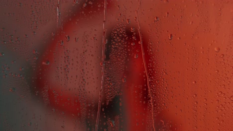 gotas de agua en una ventana en luz roja