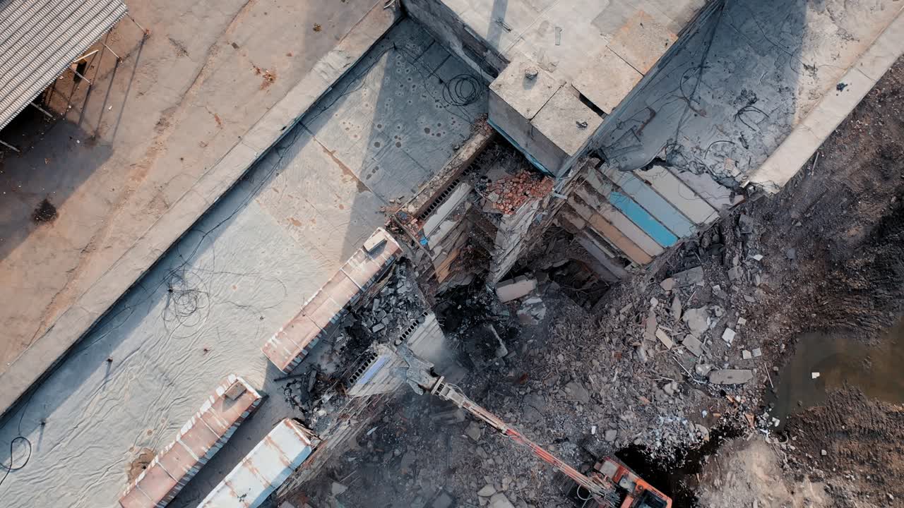 Tall building destroyed. Demolition machine tearing down roof of a wrecked building. Long machine claw pulling down the debris