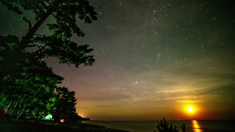 the moon rising on a starry night colors of the aurora borealis in the sky - time lapse