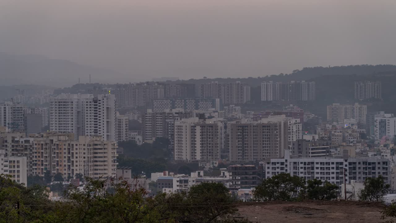 el lapso de tiempo de la puesta del sol detrás de las montañas y la transición del día a la noche del paisaje urbano, maharashtra, india