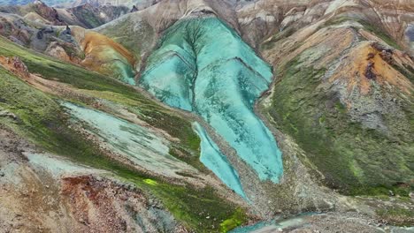 dron aéreo pequeño movimiento superior suave en la cara de grænihryggur, la roca verde, en landmannalaugar, islandia, haciendo hincapié en los tonos medios de naranja y verde