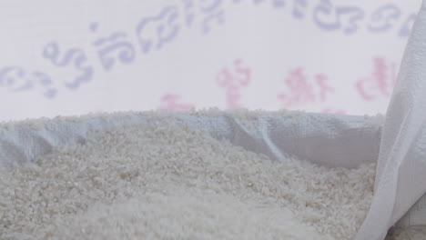 women hand filling a big canvas bag with white rice in slow motion