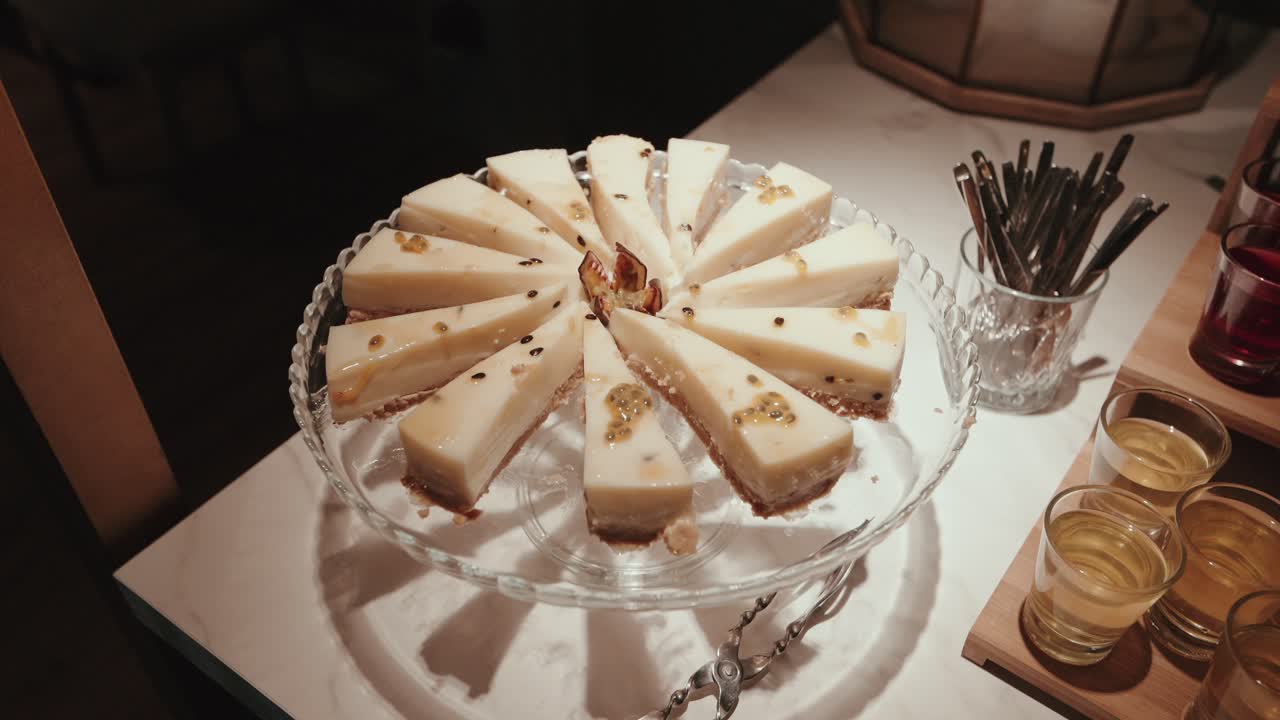 cheesecake with passion fruit topping served on glass stand in dessert table setting