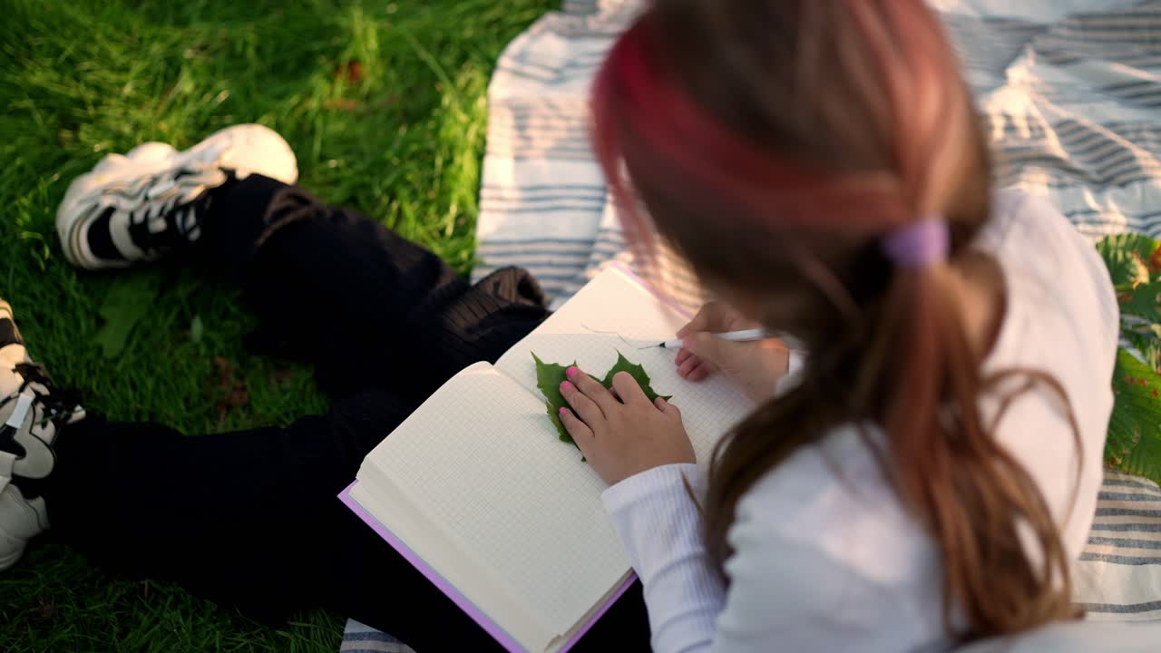 Ragazza che disegna con una foglia sull'erba