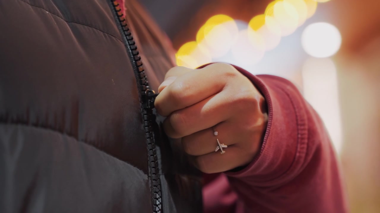 Urban evening readiness. Getting dressed for city night walk. Closeup of hands donning warm attire for night outing. Focusing on urban evening scene with coat and rings before stepping outside