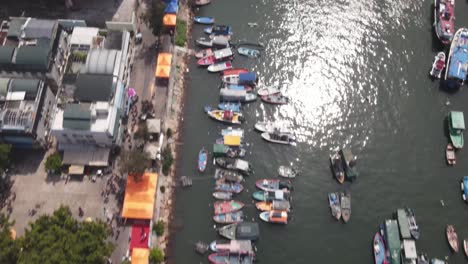 aerial birds eye view flying over marina at cheung chau island in hong kong city with tilt up reveal of small islands in background