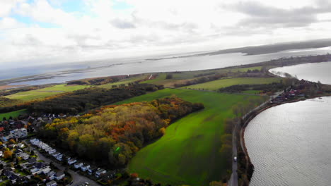 Tilted-slow-arial-downward-pan-shot-of-green-fall-peninsula-landscape-surrounded-by-bodies-of-water