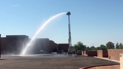 galones de agua fluyen desde la manguera contra incendios de la escalera extendida de un camión de bomberos