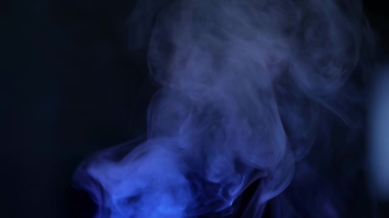 Fumo blu denso si alza in onde traslucide a strati contro uno spazio nero vuoto, creando morbide volute, sfumature lisce, bordi sfocati e un'atmosfera cinematografica a bassa luce con un forte impatto visivo astratto