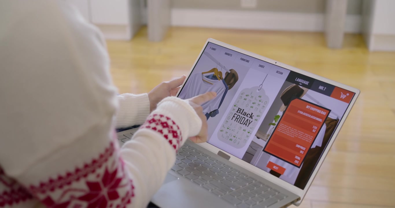 Donna con maglione bianco alla ricerca di un'offerta del Black Friday, che individua un'etichetta sul laptop, con le mani che toccano un pannello rosso