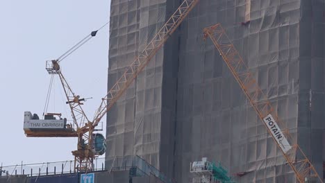 close-up view of a tower crane maneuvering materials on a high-rise building's exterior.