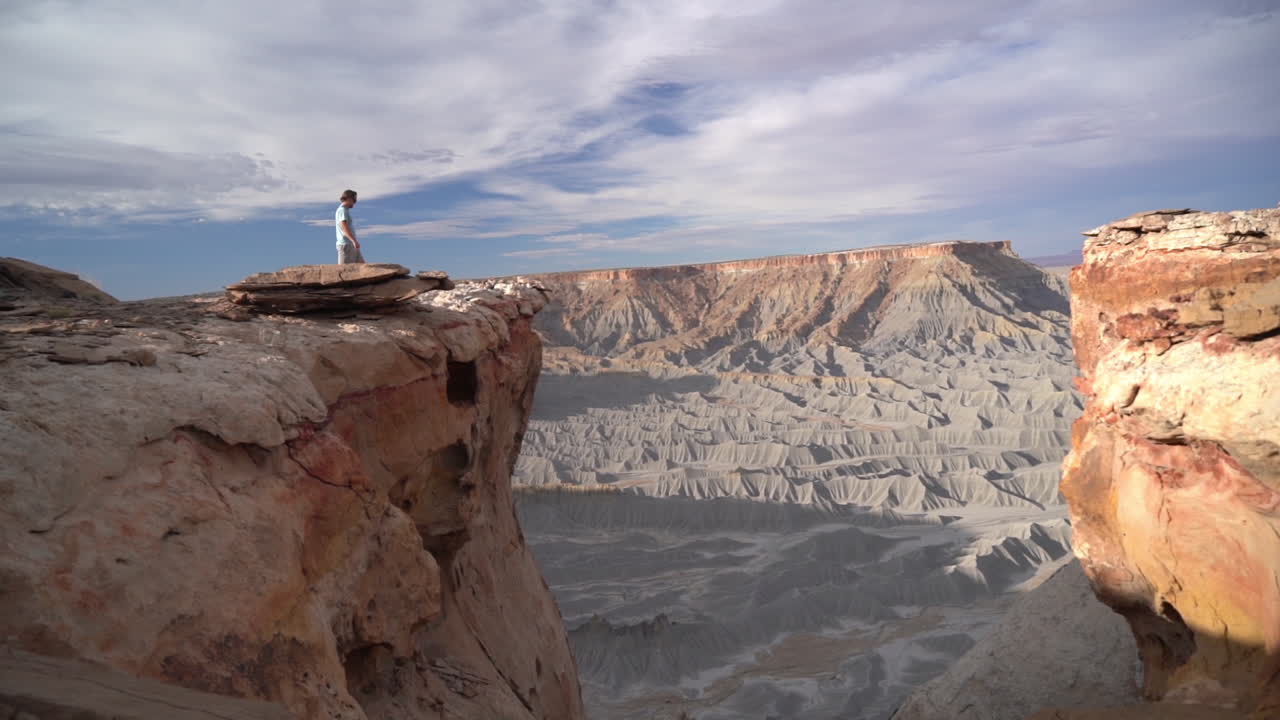 심연 위의 메사 위를 걷는 남자와 유타의 놀라운 초현실적인 건조한 사막 풍경