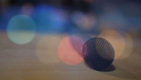 Glowing-spots-of-light-against-microphone-on-wooden-surface