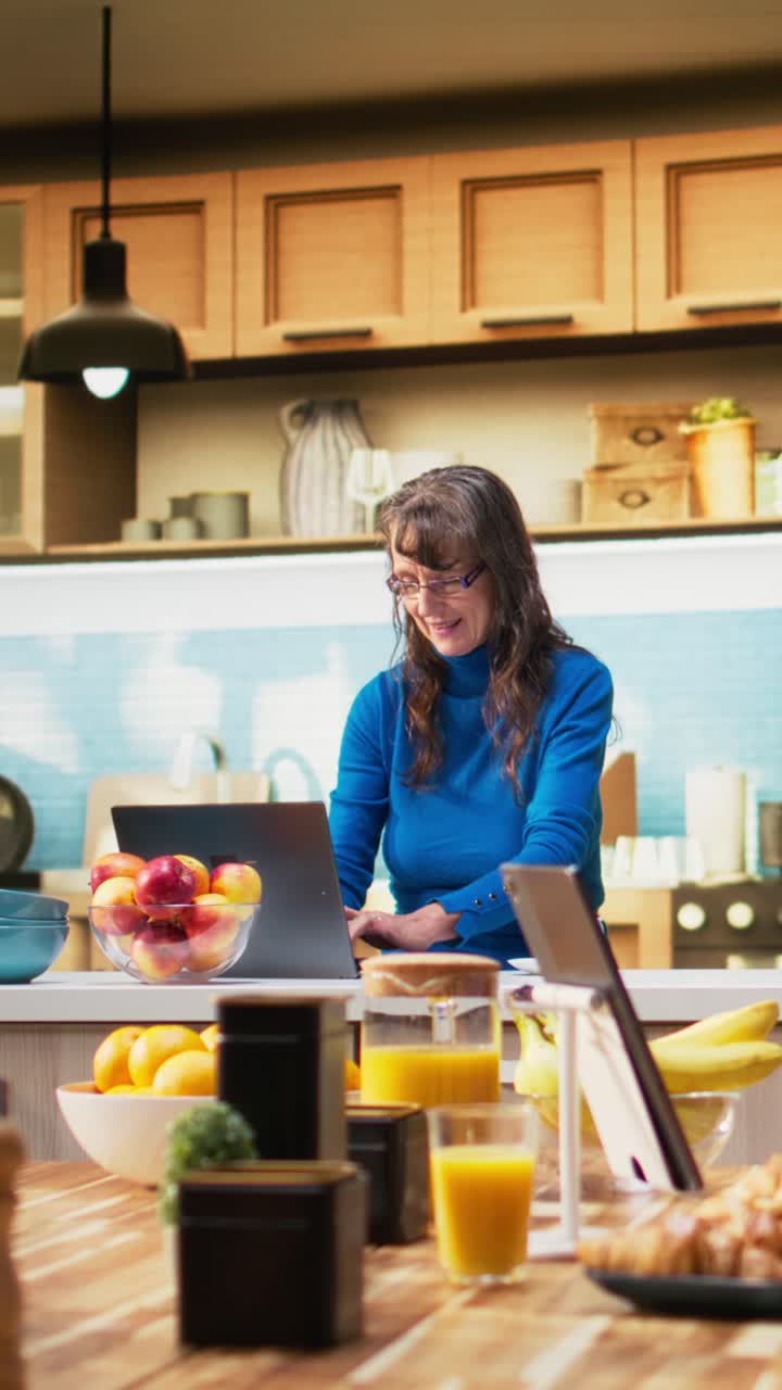 Vertical Video Senior adult browsing internet on smartphone and smiles in kitchen