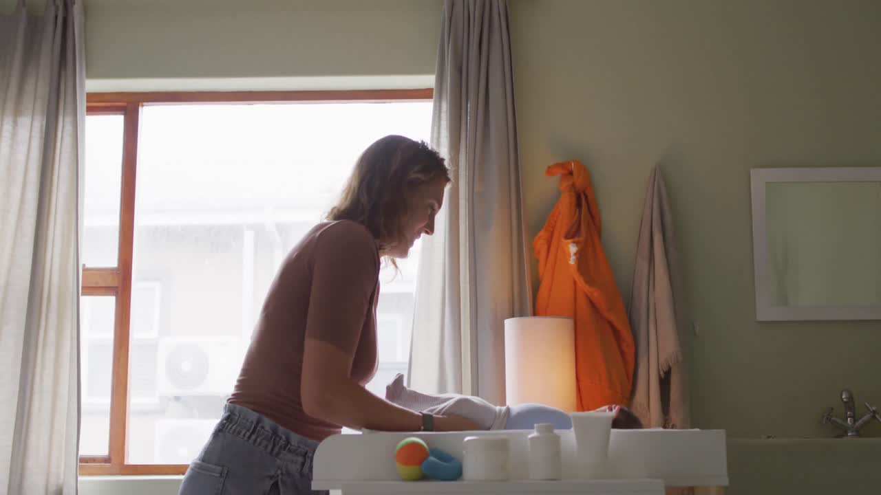 Video de madre caucásica feliz cambiando a su bebé recién nacido